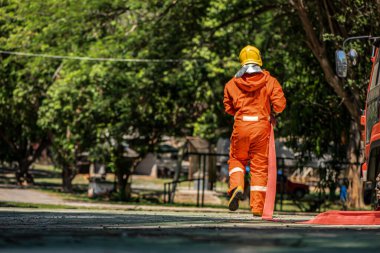 İtfaiyeciler yangın söndürme işlemleri için itfaiye araçlarından yangın hortumlarını çıkarıyorlar..