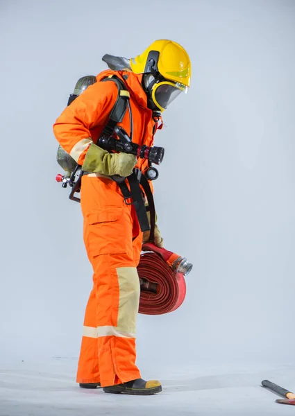 黄色のヘルメットをかぶった消防士の垂直写真が白い背景に地面に顔を下に立っている — ストック写真