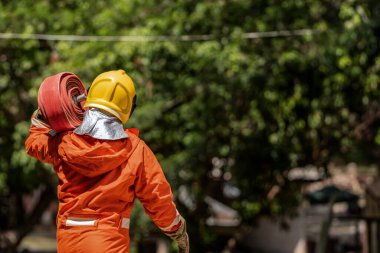 Senkronize hareketlerle, itfaiyeciler sarmalanmış yangın hortumlarını omuzlarının üzerinde taşıyorlar. Güçlü ve çevik vücutları hayat kurtaran ekipmanları yerleştirmeye hazır..