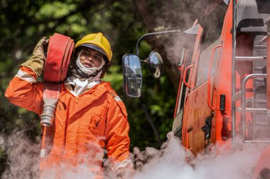 Dalgalanan duman bulutlarının ortasında, bir itfaiyeci, kendisini çevreleyen cehennemle yüzleşmeye hazır bir yangın hortumunun ağırlığıyla dimdik ayakta duruyor..