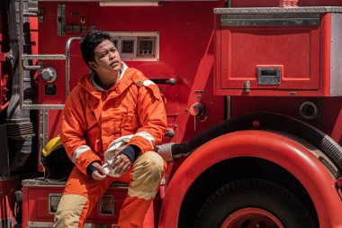 İtfaiye aracına yaslanan itfaiyeci geriye yaslanır ve başını yukarı kaldırır. Gözlerini gökyüzünün enginliğine diker ve operasyonun yoğun taleplerine kısa bir ara verir..