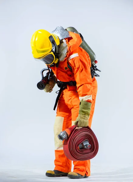 清潔で中立的な背景を背景に 消防ホースを保持する消防士は 生命を守るために危険に直面している人々が示す最前線の英雄と献身を表します — ストック写真