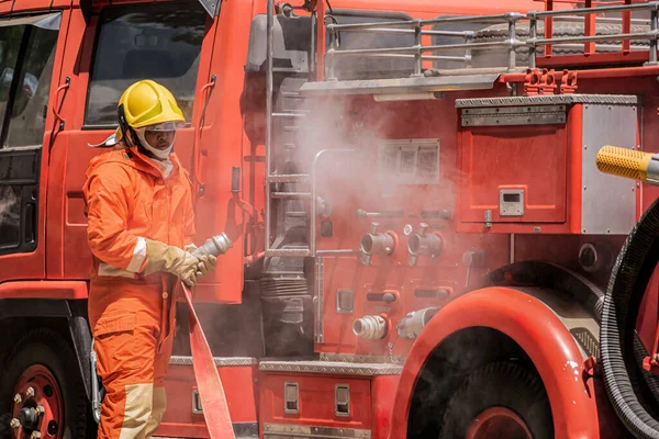 Незмінною Рішучістю Пожежник Стоїть Високо Поруч Пожежною Машиною Міцно Тримаючи — стокове фото