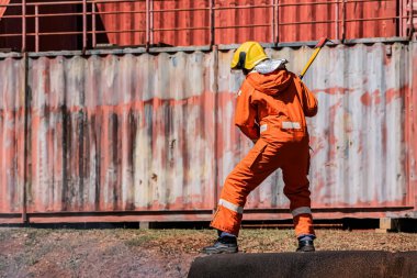 Açık havada bir itfaiyeci dimdik ayakta duruyor ve demir bir baltayı sarsılmaz bir güçle tutuyor..