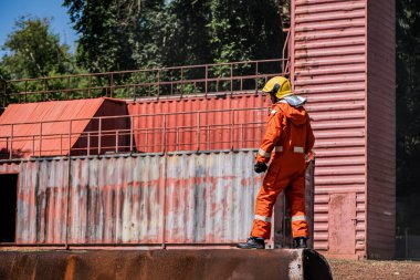 Profesyonel itfaiyeciler dışarıdaki paslı bir binanın tepesinde duruyorlar..