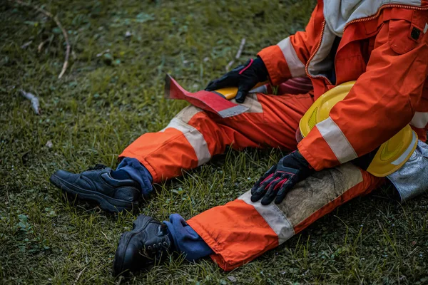 消防士の頑丈な存在と草の柔らかさのコントラストは 緊急時の準備をしながら 異なる環境に適応する能力を強調しています — ストック写真
