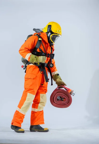 彼の背中に酸素タンクと白い背景に床を探している間 プロの消防士が立って 消防ホースを保持 — ストック写真