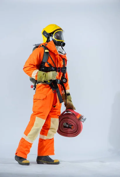 プロの消防士が消防ホースを持って横に立っていて 白い背景に酸素タンクを背負ったまま — ストック写真