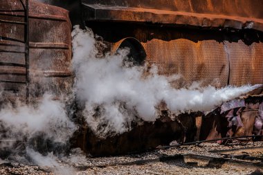 Girdap gibi dönen dumanın ortasında, paslı bina kasvetli duruyor..