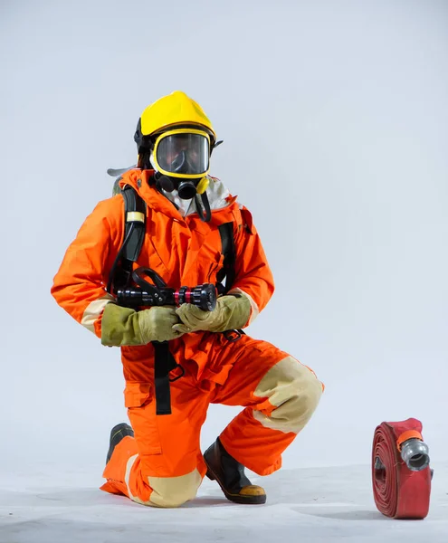 Profesjonalny Strażak Żółtym Hełmie Klęczy Gdy Wąż Strażacki Leży Podłodze — Zdjęcie stockowe