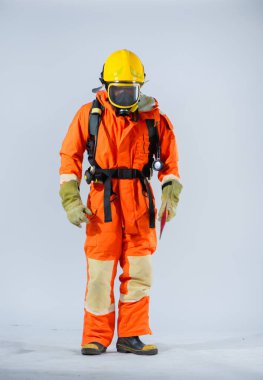 Profesyonel itfaiyeci, el değmemiş beyaz bir arka planda demir baltayı sıkıca tutarken bakışları yere doğru odaklanmış olarak duruyor..