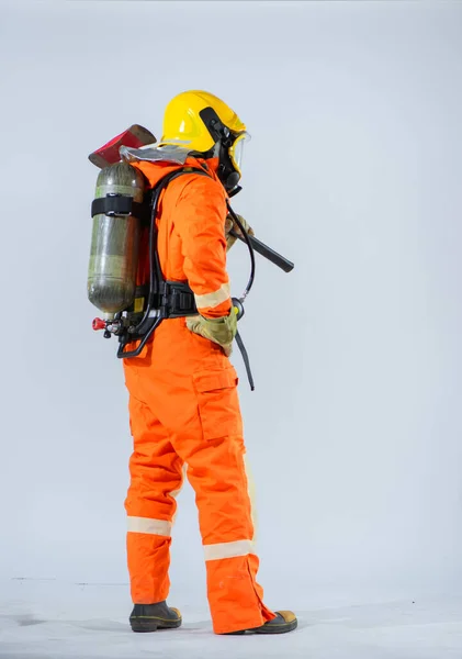 彼の背中に目立つプロの消防士の保護酸素タンクは 彼が英雄的な任務を遂行するために頼る重要な機器を思い出させる役割を果たしています — ストック写真