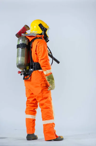 後ろから見ると プロの消防士は 鉄斧を手にしっかりとしっかりと保護酸素タンクを握りしめている不動の姿勢で立っています — ストック写真
