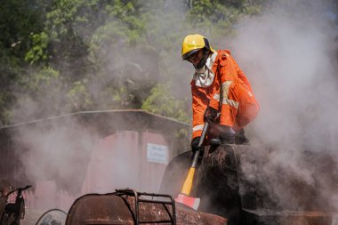 İtfaiyecinin elleri demir baltayı sıkıca kavrıyor ve dumanın ve gittikçe kötüleşen ortamın ortasında bekleyen zorlu görevlere karşı olağanüstü fiziksel gücünü ve hazırlığını gösteriyor..