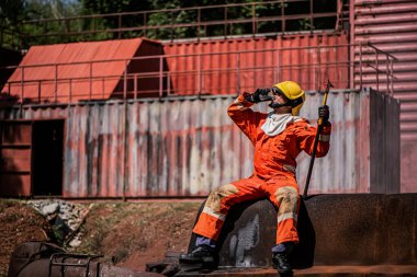 Profesyonel itfaiyeci paslı binada oturuyor ve açık havada susuzluktan içme suyu içiyor..