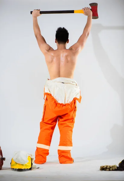 stock image From a back view perspective the professional firefighter stands and confident while holding an iron axe and lodge to the top showcasing his strength and readiness for action with his muscular.