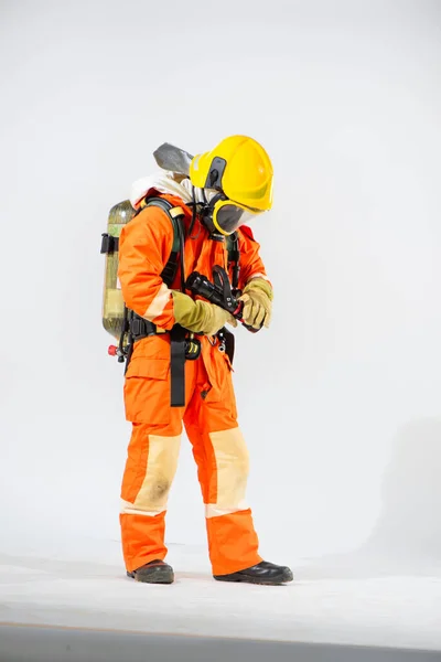 黄色の硬い帽子をかぶったプロの消防士が立っており 両手で準備を確認し 彼の背中に酸素タンクを身に着けている消防ホースを保持しています — ストック写真