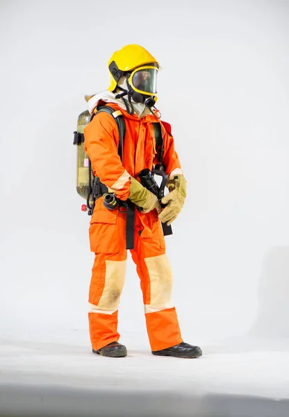 白い背景に両手で消防ホースを保持立って黄色のハード帽子を身に着けているプロの消防士 — ストック写真