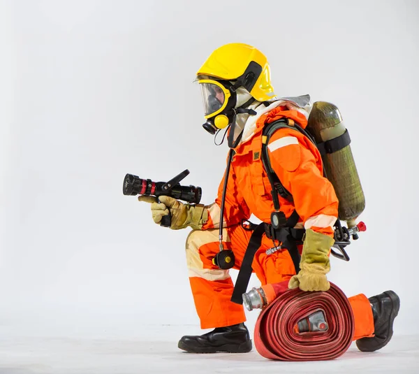 炎のホースを手でしっかり握っている間 白い背景にひざまずいて消防士は強く 安定した姿勢を維持します — ストック写真