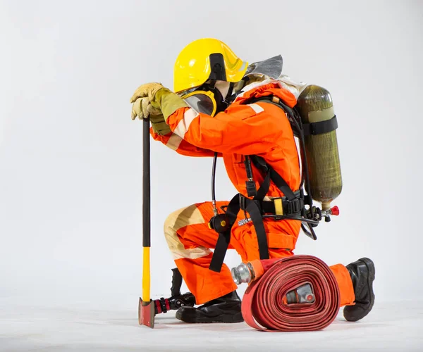 ケニング消防士は白い背景に向かって彼の背中に酸素タンクを用意して地面に彼の斧を押す — ストック写真