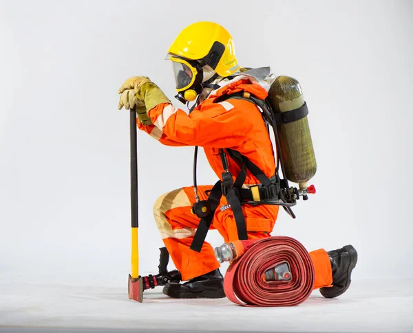 消防士は身をかがめて斧を地面に突きつけ 白い背景に酸素タンクを背負ったまま地面に突き出した — ストック写真