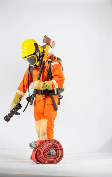 黄色のハード帽子とマスクを身に着けている消防士は 白い背景に地面を見下ろす彼の肩に斧で立っている — ストック写真