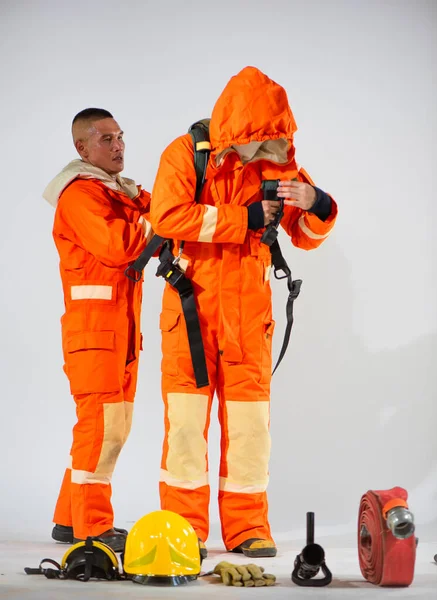 プロの消防士は 彼のパートナーが白い背景に彼の酸素タンクを置くのを助けるコミットメントです — ストック写真