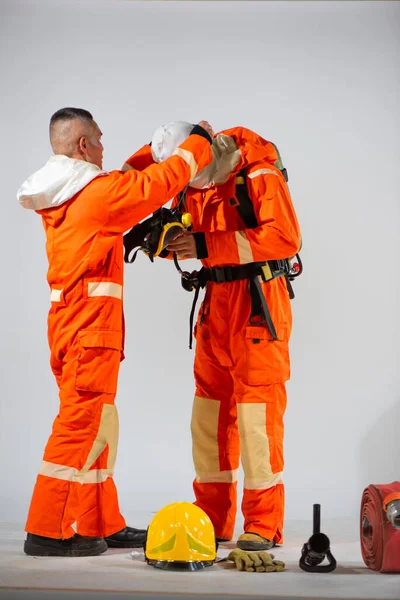 プロの消防士は慎重に彼のパートナーの安全のためにそれを行う前に その整合性と機能性を確保マスクを検査 — ストック写真