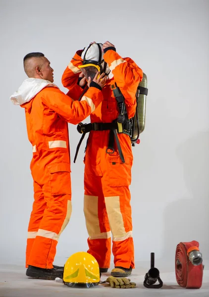 プロの消防士は それが安全かつ快適に最適な機能のために彼のパートナーの顔に座っていることを保証マスクに正確な調整を行います — ストック写真