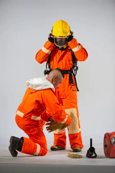 stock image Professional firefighter carefully examines the quality of gloves, ensuring they meet the standards before fitting them onto his partner's hands.