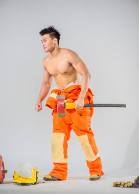 İtfaiyeci, beyaz arka planda demir baltayla durup insanları kurtarırken hazırlık pozisyonunda duruyor..