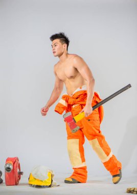 Profesyonel itfaiyeci, demir baltayı sıkıca kavrayarak önüne çıkabilecek her türlü itfaiye mücadelesine hazır bir şekilde kendinden emin bir şekilde ayakta duruyor..