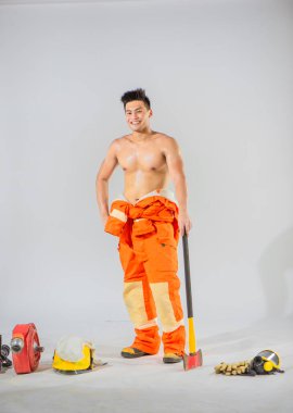 Profesyonel itfaiyeci, fiziksel hünerini ve eylemlerine hazır olduğunu göstermek için zemine destek ve istikrar sağlamak için demir bir balta ile ayakta duruyor..