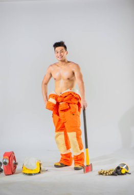 Profesyonel itfaiyeci, beyaz arka planda demir bir baltayla, yüzünde gülümsemeyle zemini destekliyor..