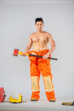 İtfaiyecinin gülümsemesi ve demir baltayı tutarken duruşu zorluklarla karşılaştığında hızlı hareket etmeye hazır olduğunu gösteriyor..