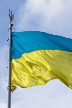 Ukrayna bayrağı rüzgarda dalgalanıyor. Mavi-sarı bayrak armalı