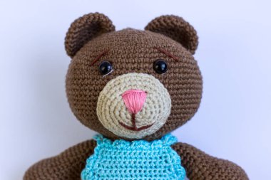 Beyaz arka planda mavi takım elbiseli kahverengi bir ayı. Şirin örülmüş ayı.