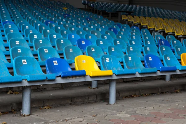 Yellow among the blue seat in the spectator arena. Seat for fans. Seats at the stadium