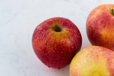 Beyaz mermer bir masada kırmızı-sarı elmalar