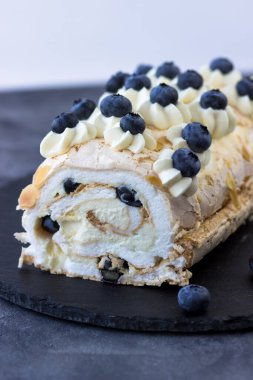 Koyu arkaplanda kremalı pasta rulosu. Yaban mersinli tatlı