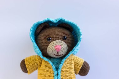 Beyaz arka planda mavi takım elbiseli kahverengi bir ayı. Şirin örülmüş ayı.