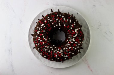 İştah açıcı çikolatalı kekin en üst görüntüsü. Kek kremayla kaplı ve kırmızı kalplerle süslenmiş.