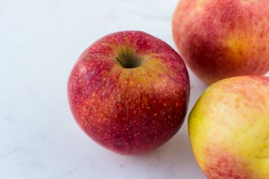 Beyaz mermer bir masada kırmızı-sarı elmalar