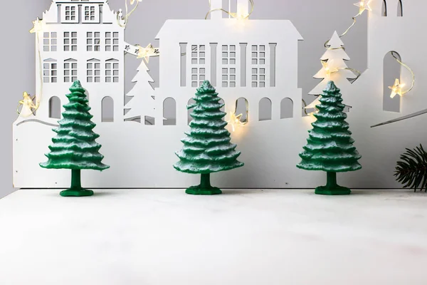 New year, christmas background. Three snow-covered spruce trees on the background of a wooden city