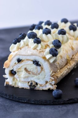 Koyu arkaplanda kremalı pasta rulosu. Yaban mersinli tatlı