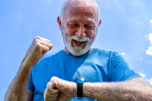 Portrait of a senior man checking his watch. The elderly sportsman controls his heart rate and blood pressure by monitoring the smartwatch on his wrist, happy with the results. Healthcare.