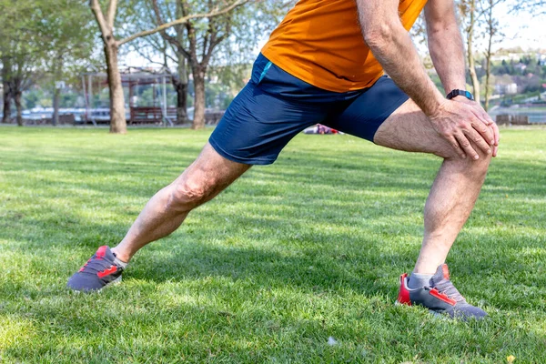 stock image Determined senior man exercise in the park. Active elderly male stretching his legs.