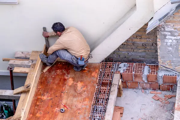 The construction engineer checks the quality of the performed work on the rooftop and terrace structure of the house.