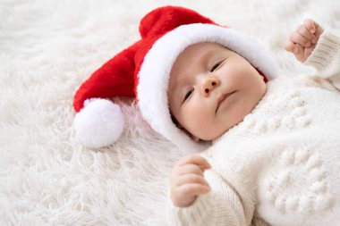 Noel Baba şapkası takan ve küçük sevimli bir kardan adam oyuncağına sarılan yeni doğmuş tatlı bir kızın Noel portresini kapat.