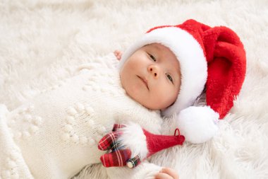 Noel Baba şapkası takan ve küçük sevimli bir kardan adam oyuncağına sarılan yeni doğmuş tatlı bir kızın Noel portresi.